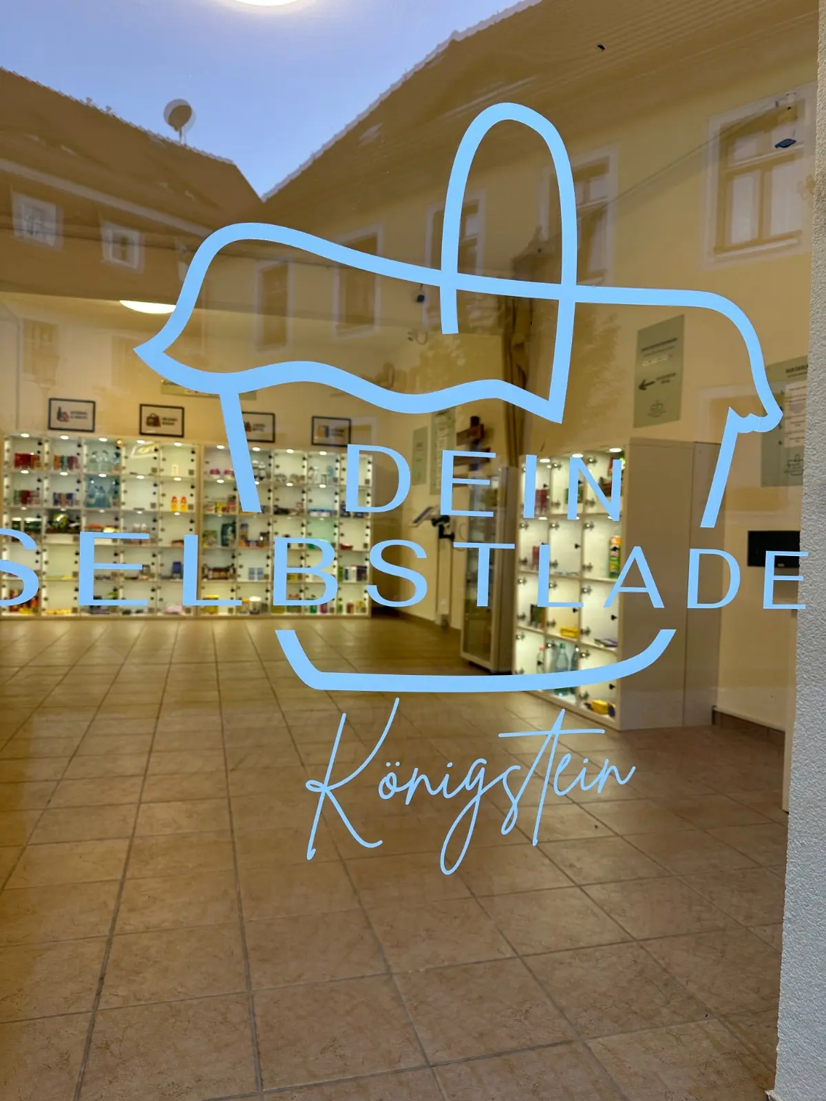 Beleuchteter Eingang des Selbstladen am Abend